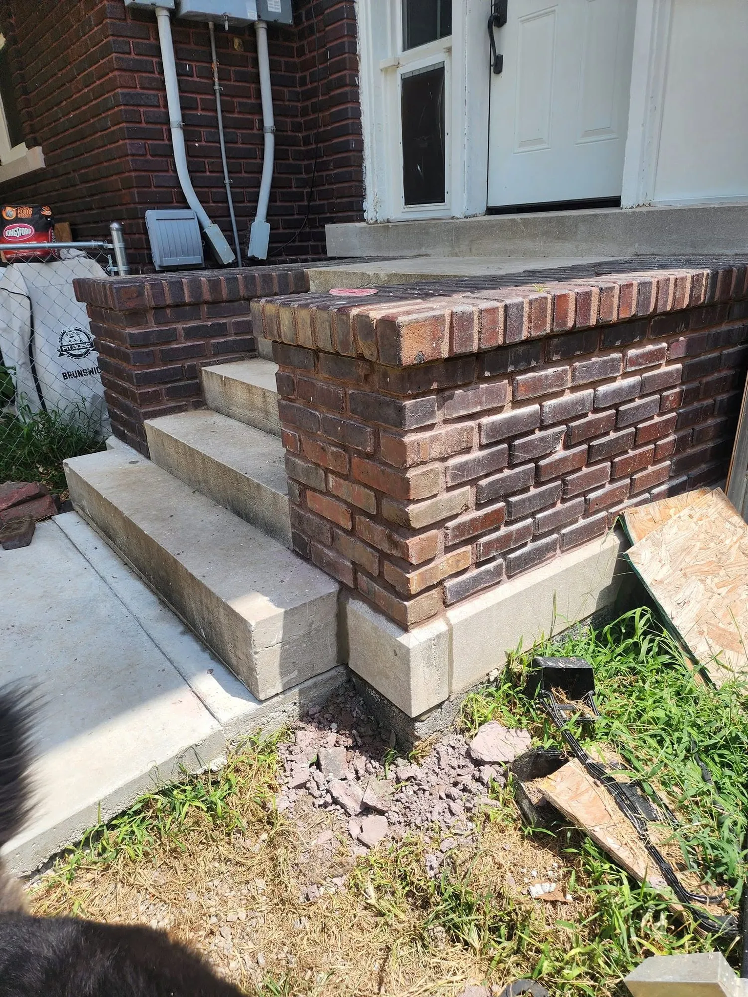 New concrete steps framed by dark red brick knee walls with rowlock brick caps