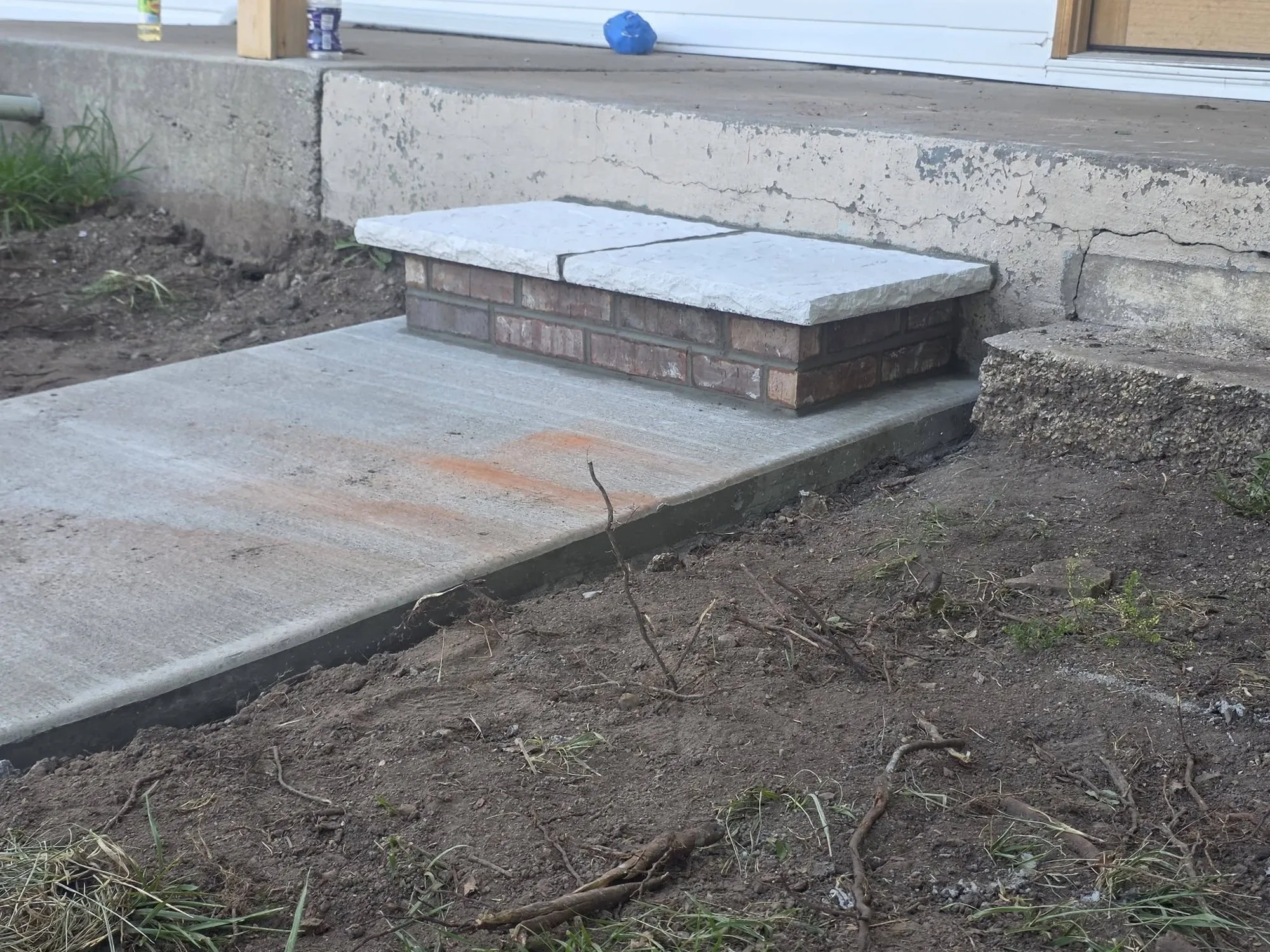 Brick entry step with two-piece rock-face stone cap set on a new concrete walkway