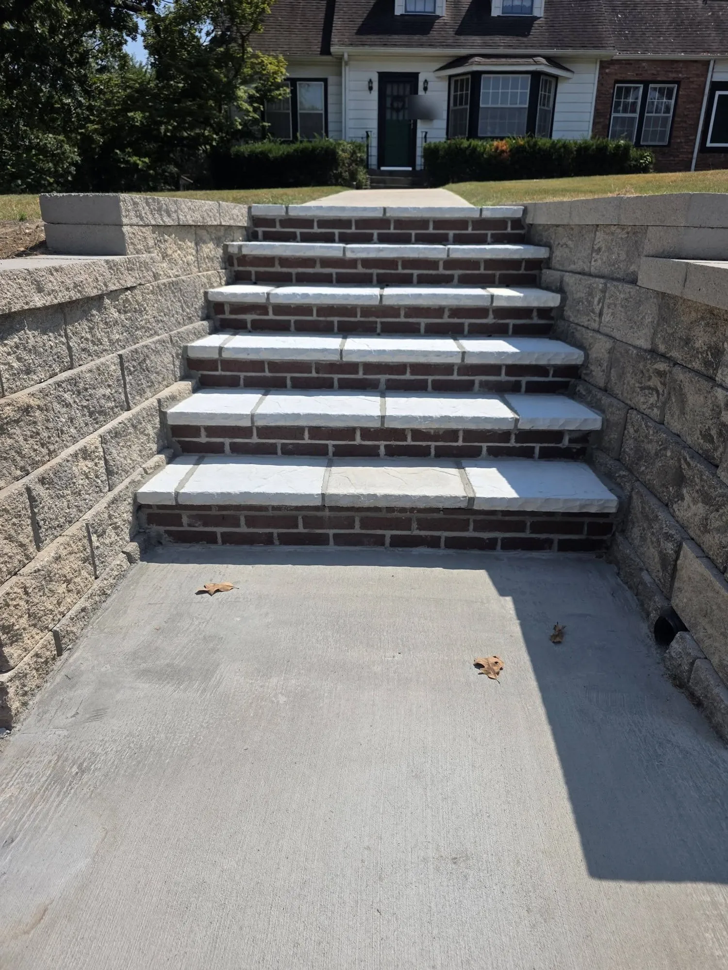 Close-up of new steps with red brick risers and rock-face stone treads set between block retaining walls