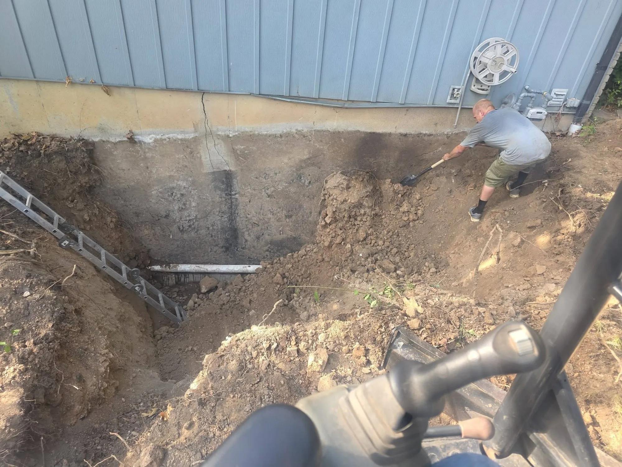 Foundation wall dug out to the footing showing a vertical crack before repair