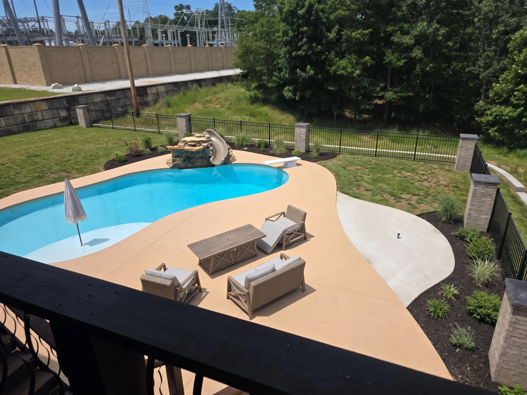 Backyard pool with stained concrete deck, brick fence columns with stone caps and new landscape beds