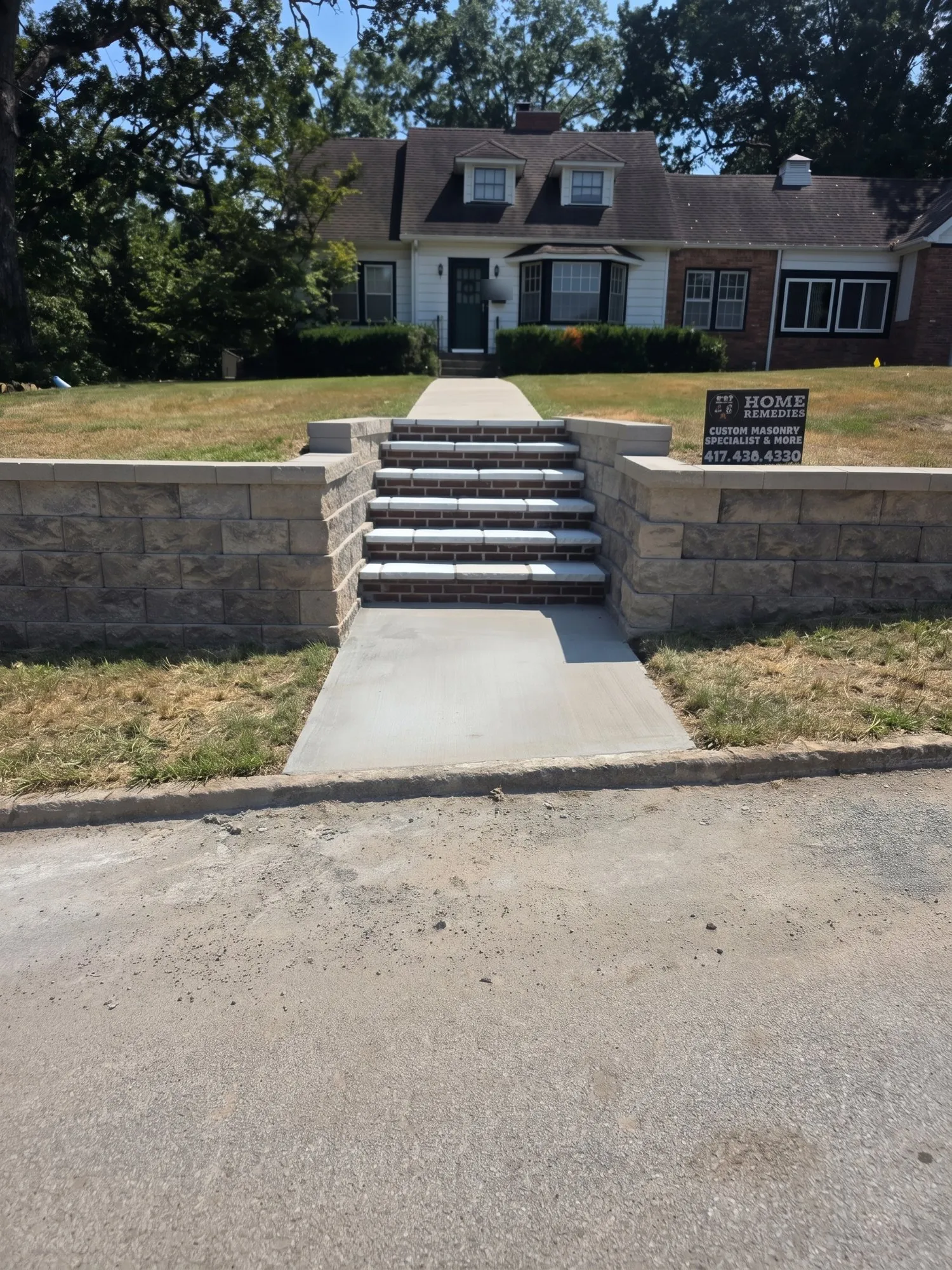 Segmental block retaining wall along a street with brick risers, stone stair treads and a new concrete landing