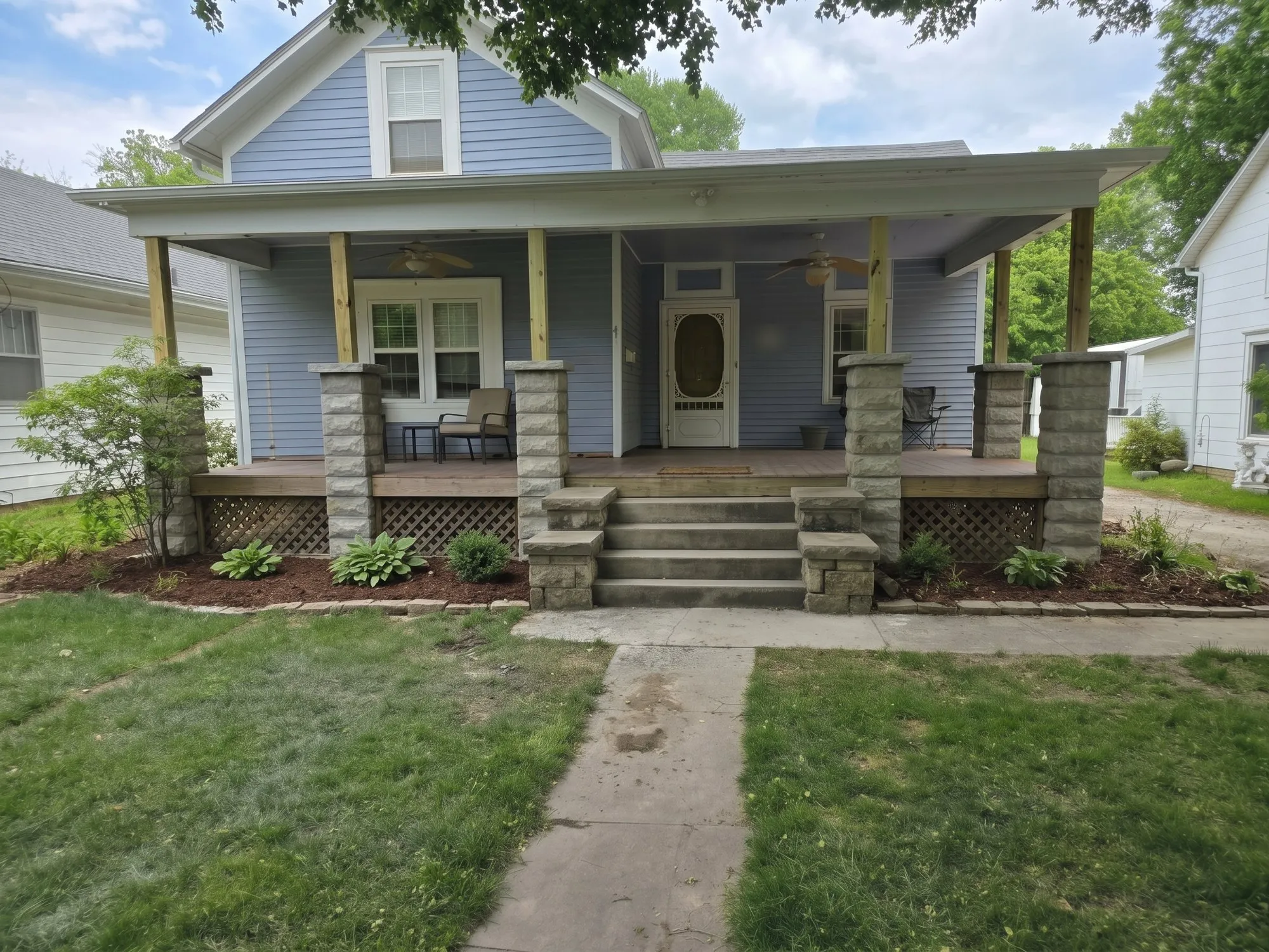 Front porch with new split-face stone columns, stone-capped steps and paver-edged landscape beds on a home in Joplin, MO