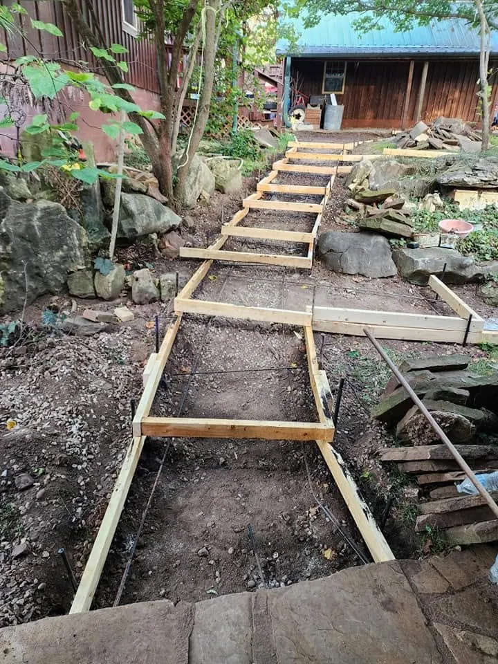Wood forms and rebar set for a new concrete walkway with steps down a sloped backyard